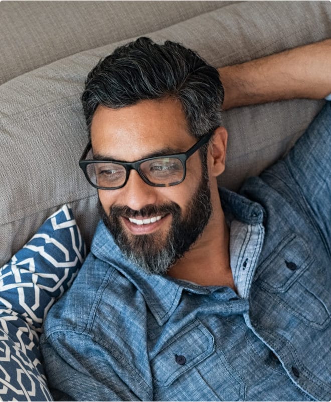 Man sitting on the couch with glasses, smiling