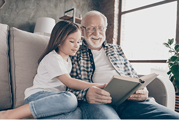 An older man reads a book on hearing loss to his granddaughter in their Arkansas home. 