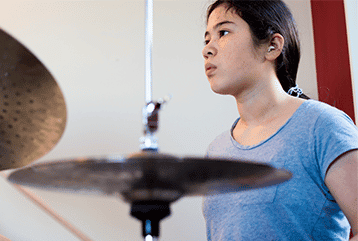 A drummer in Tennessee wears ear plugs to help prevent hearing loss during her concert. 